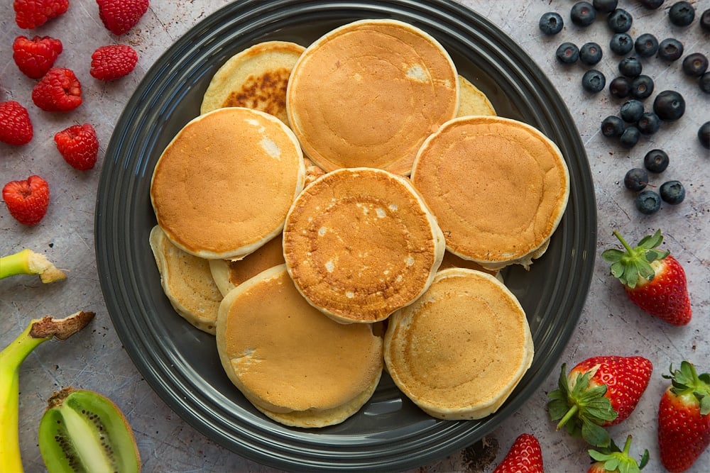 Freshly cooked pancakes, shown surrounded by fruit