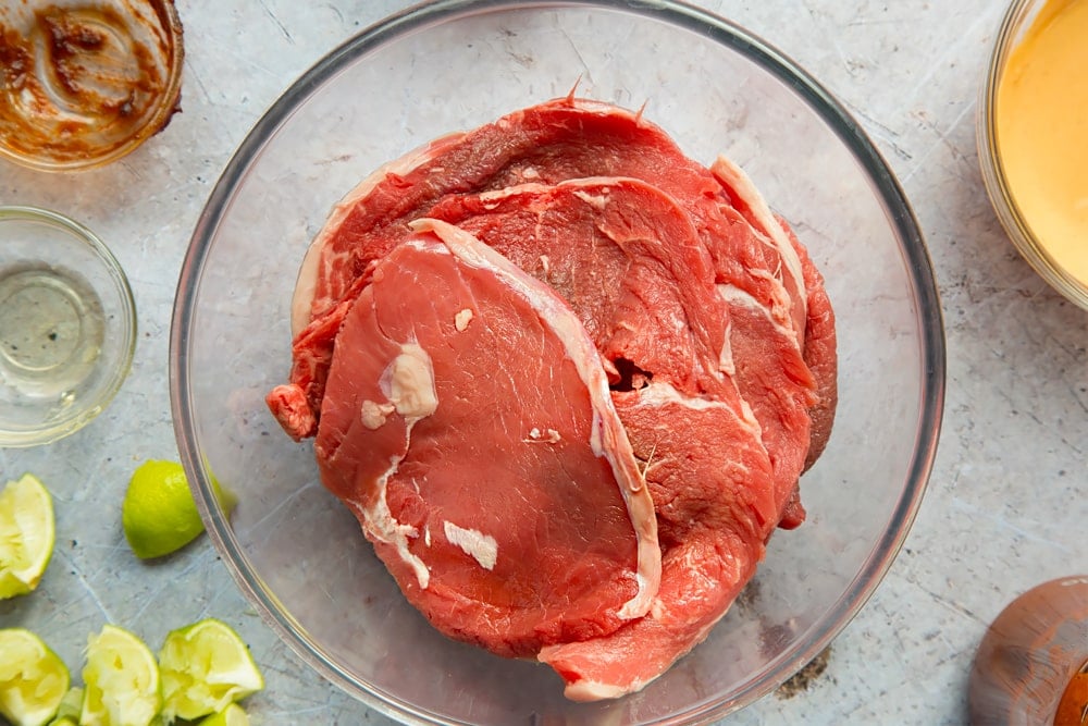 The steaks are shown here in a glass bowl, ready to be marinated 