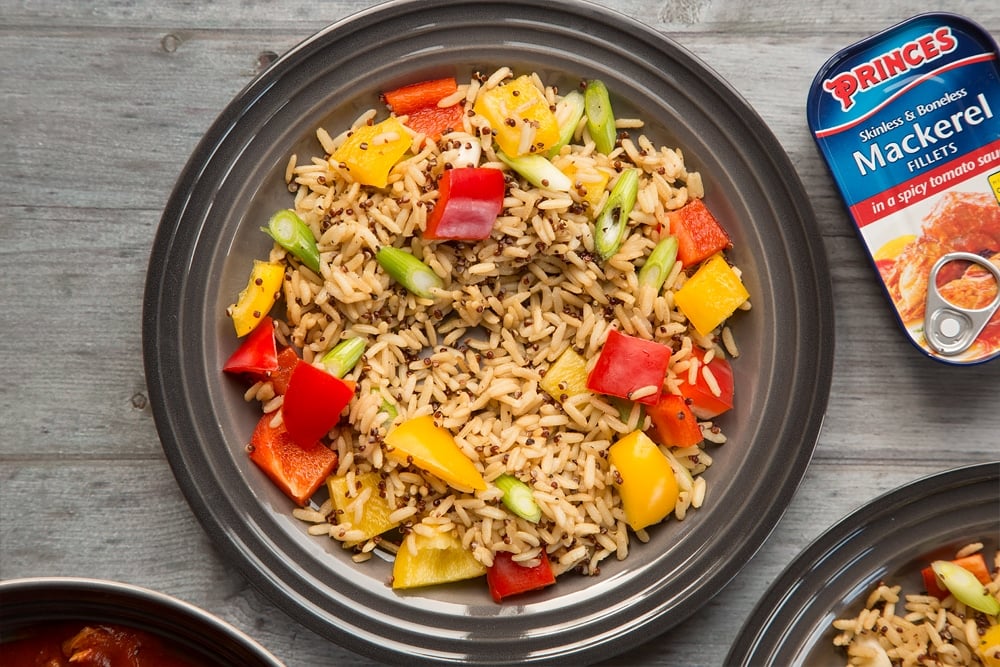 The rice with mixed vegetables is then served onto two plates, ready for the mackerel to be added