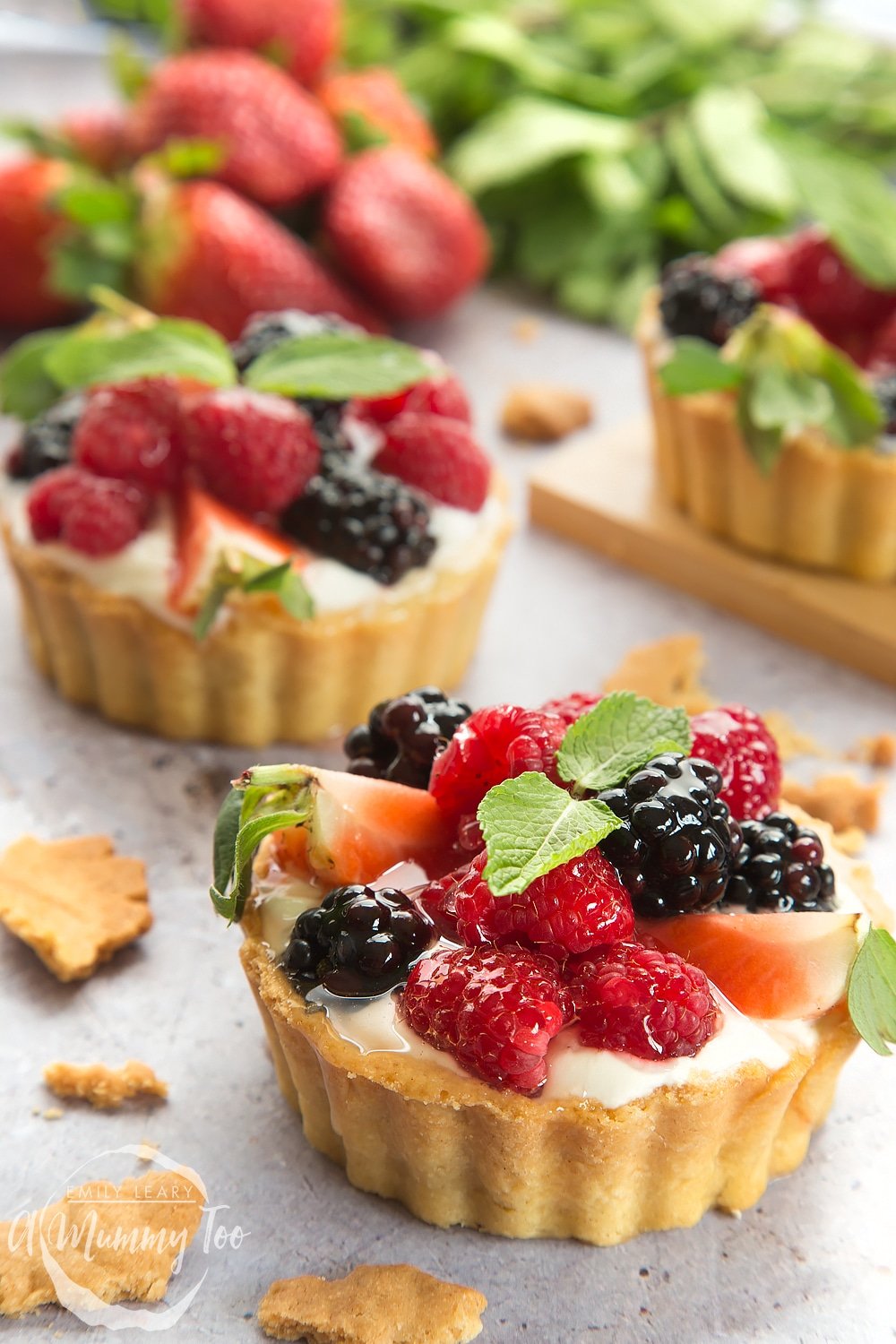 Whipped yogurt fruit tarts in a pastry case topped with mint 