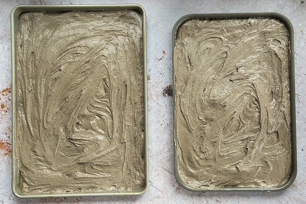 The cake mix is spread around the tins and leveled out, ready for baking