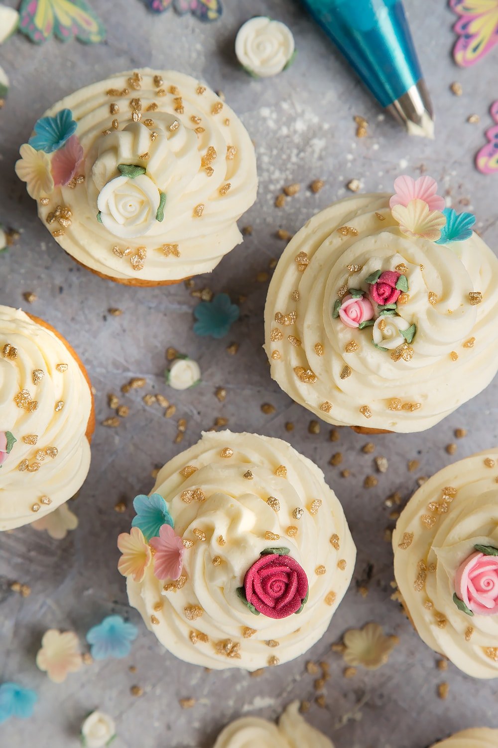 Top the lemon cupcakes with your choice of decorations - shown here are sugar roses, flowers and gold decorations