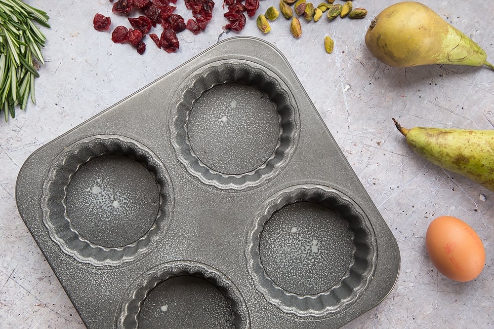 A tartlet tin, greased - shown alongside pears and rosemary