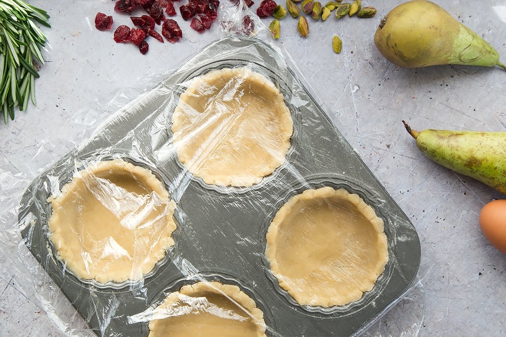 The tart bases are covered in cling film and left to set, while the rosemary goat's cheese filling is prepared