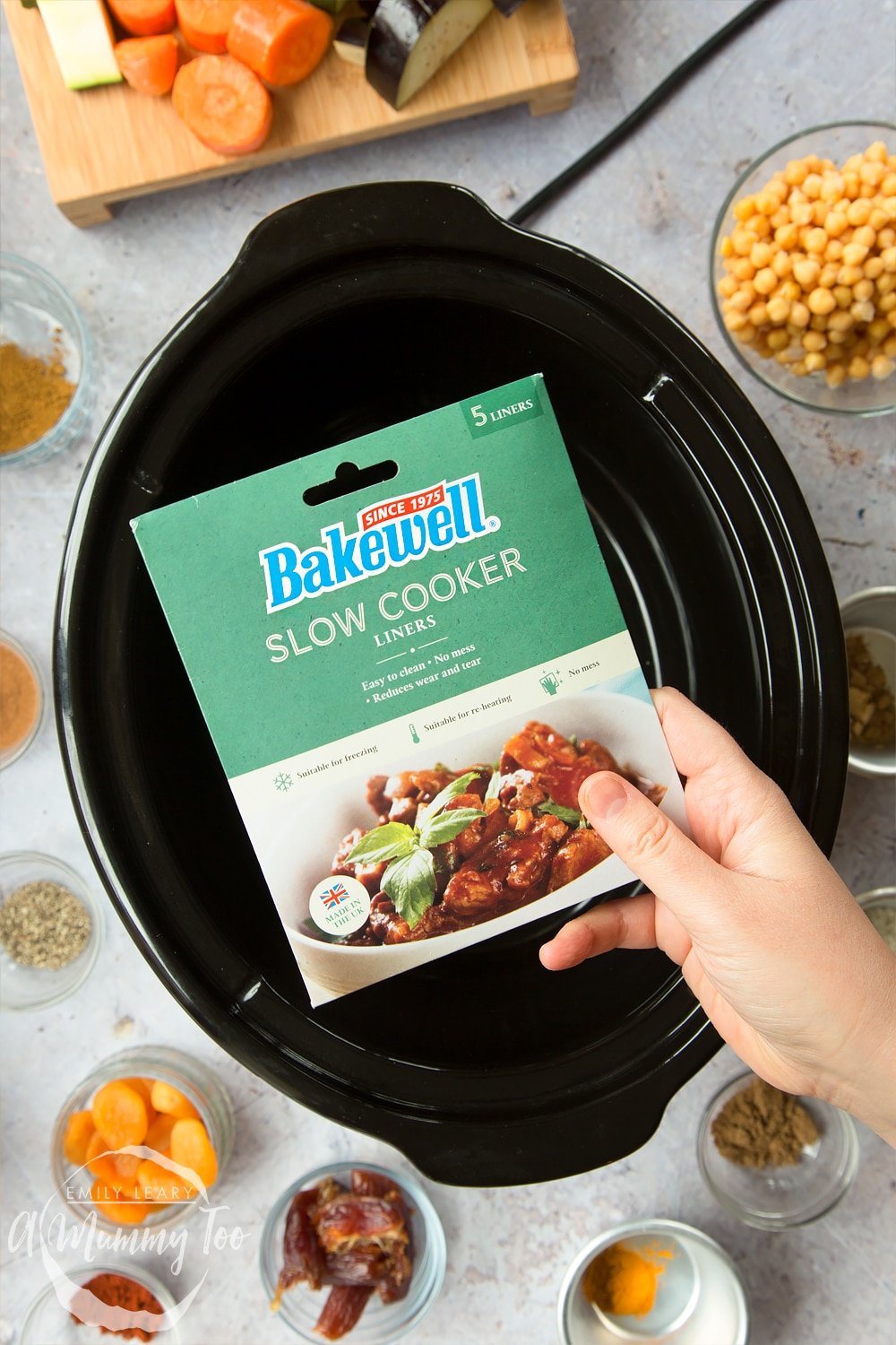 an empty slow cooker black ceramic dish with a hand holding Bakewell Slow Cooker Liners in front.