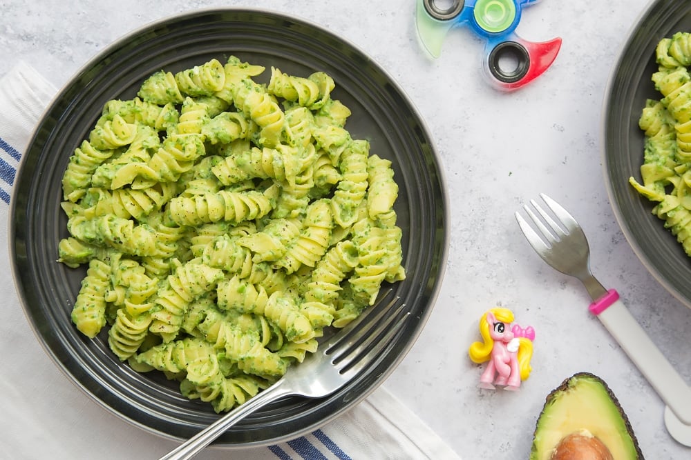 Pasta mixed with green pasta sauce, served in a bowl ready to eat