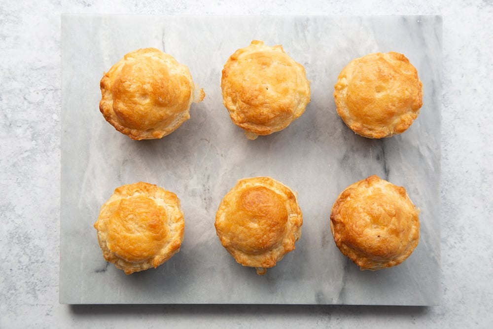 Six finished pies on a marble chopping board.