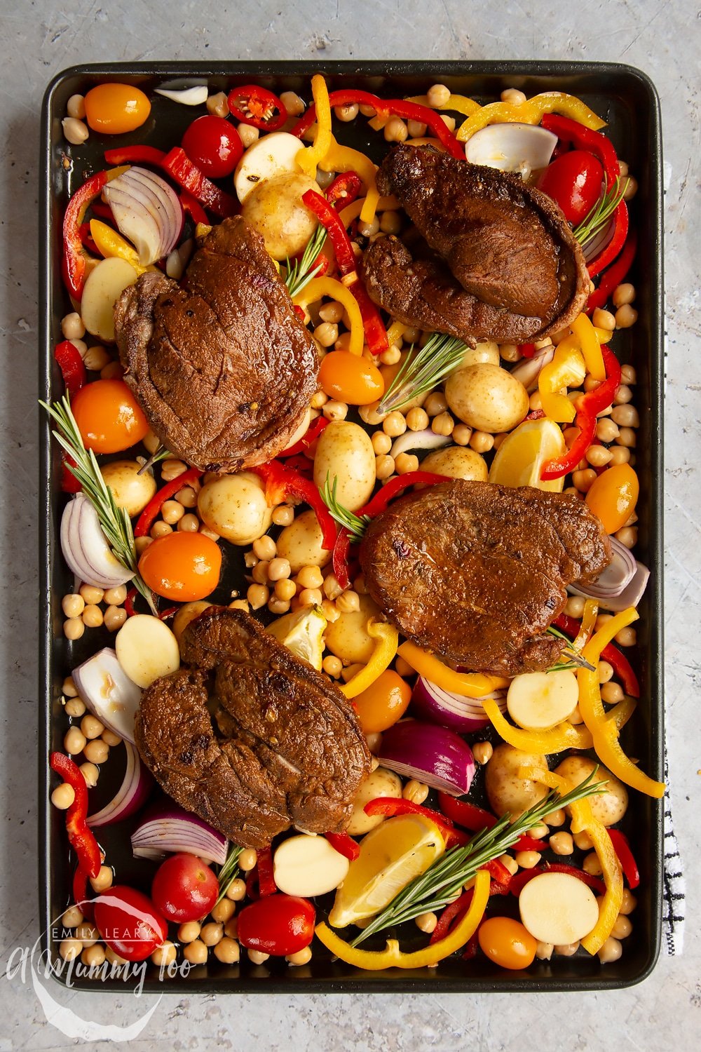 Lamb steaks placed on top of the vegetables and rosemary