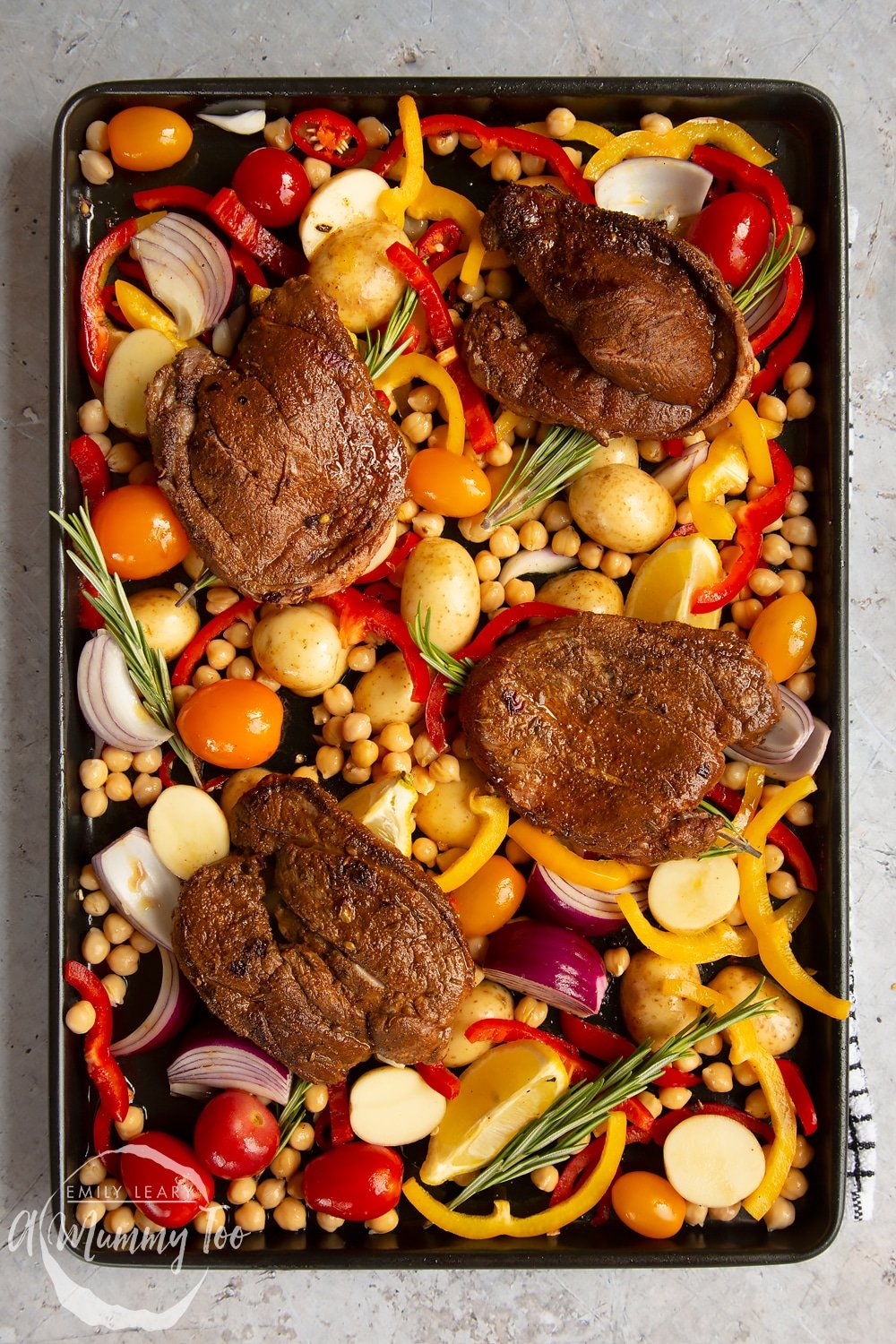 Lamb steaks placed on top of the vegetables and rosemary 