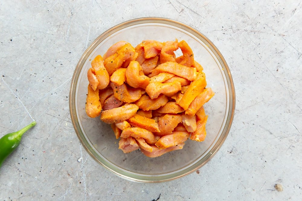 Seasoned strips of pork in a glass bowl