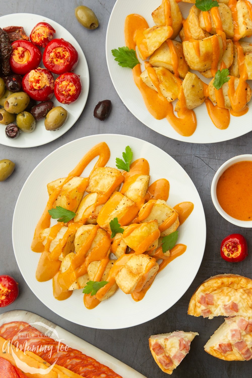 spicy patatas bravas served onto white plates with other tapas items