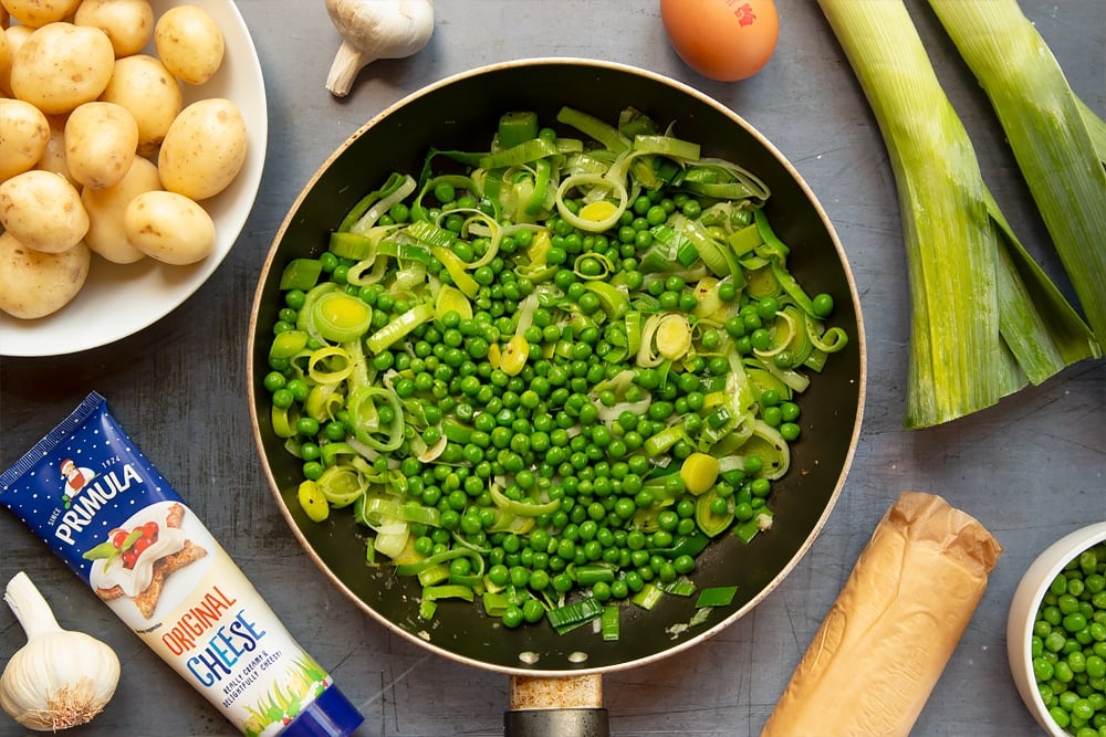 Peas are added to the vegetables in the pan