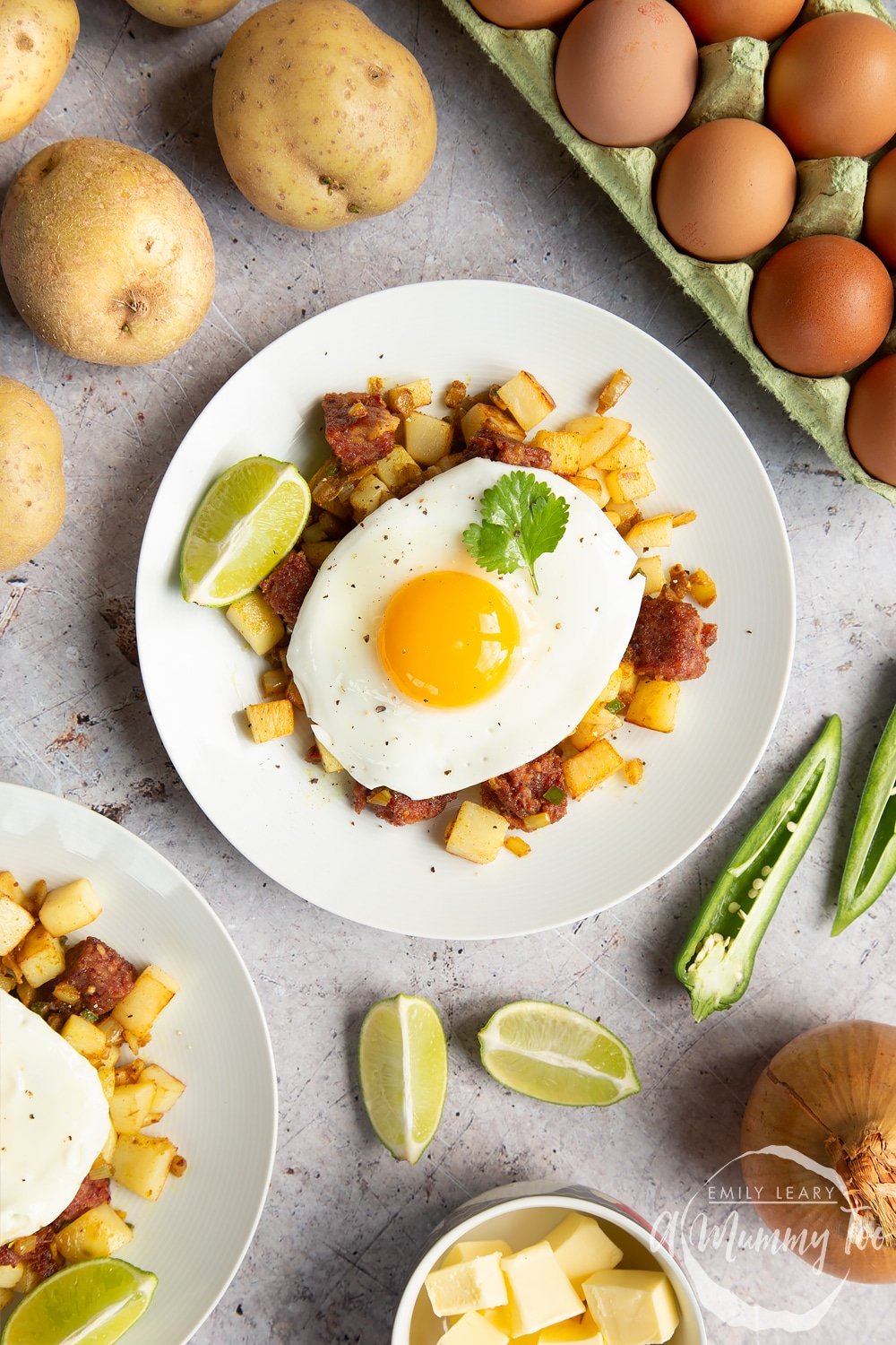 Curried corned beef hash topped with a fried egg, surrounded by raw ingredients 