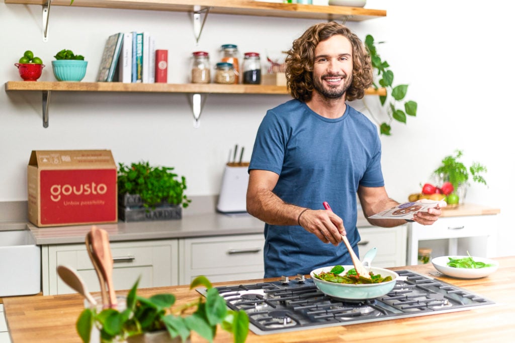 Joe Wicks cooking in a kitchen with a Gousto box in the background