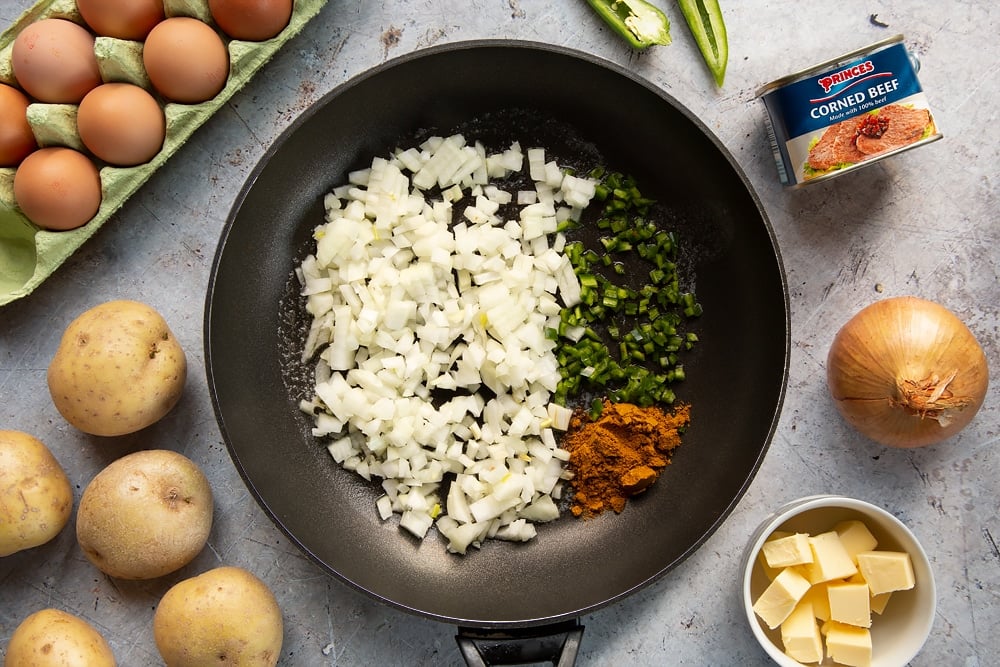 Chopped onions, curry powder and green chilli in a frying pan