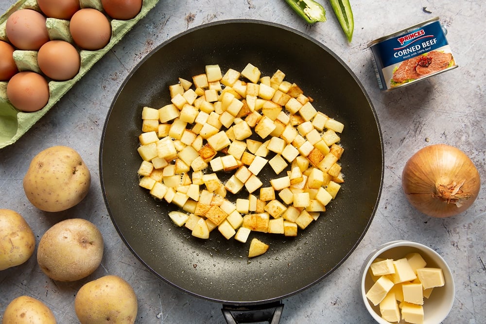 Golden potato cubes in a frying pan