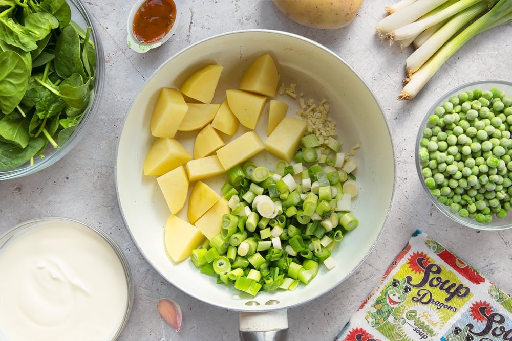 Spring onions, potato and garlic in a large pan