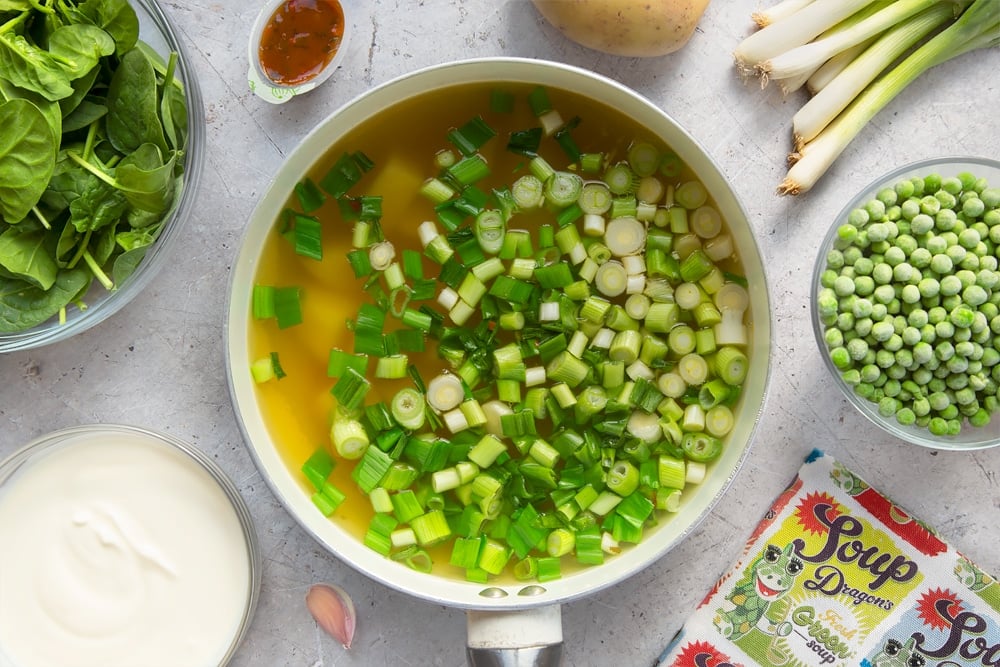 Fresh green soup ingredients and vegetable stock, boiling in a pan