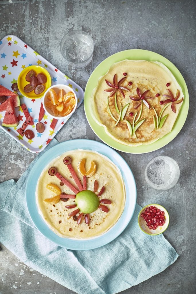 Overhead shot of Pancake Art served on a blue and green plate topped with fruits