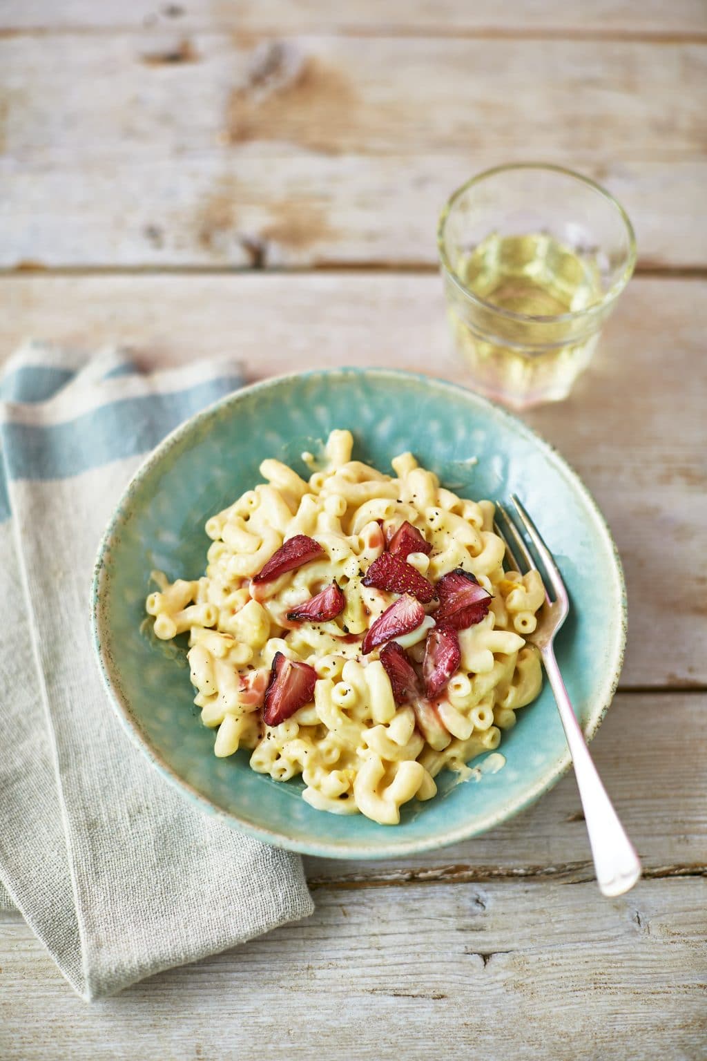 Front angle shot Strawberries Cream Pasta served on a teal bowl with a fork on the side