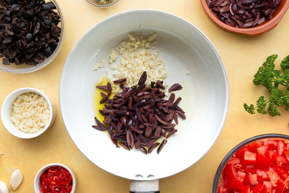 One large pan with rinsed olives and capers ready to create spaghetti alla puttanesca