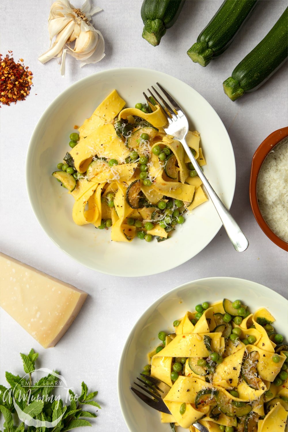Jamie Oliver's courgette and pea pasta, served to two bowls, surrounded by ingredients.