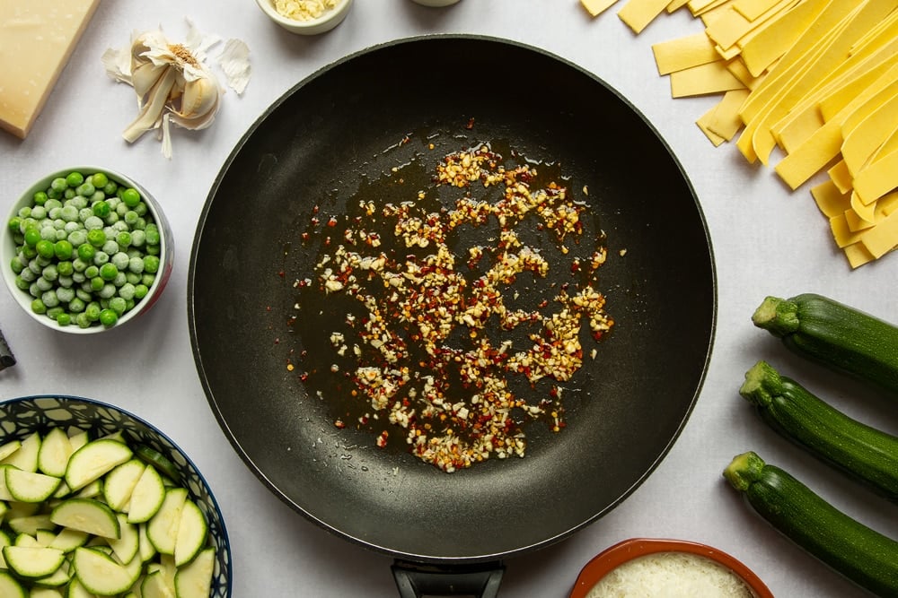 Garlic, oil and chilli flakes fried in a frying pan.