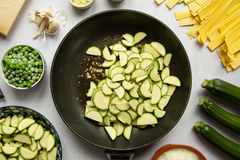 Garlic, oil and chilli flakes fried in a frying pan. Courgette slices added.