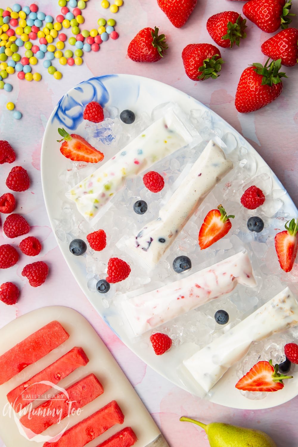 large plate covered in ice with 4 fruit yogurt ice pops on top decorated with fruit