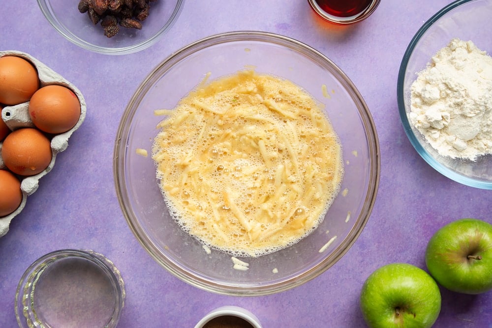 No junk apple and strawberry muffins - grated apple, eggs, maple syrup and oil mixed in a bowl.