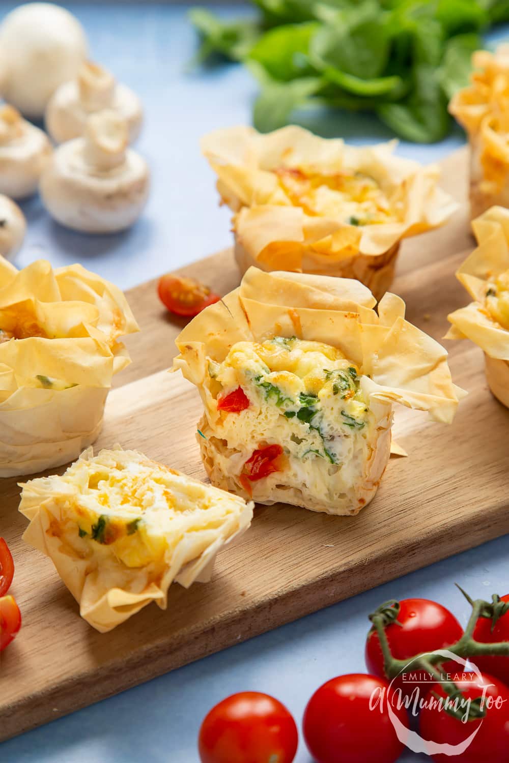 Filo pastry mini quiches - cut open to show the cooked filling with pieces of tomato and spinach.