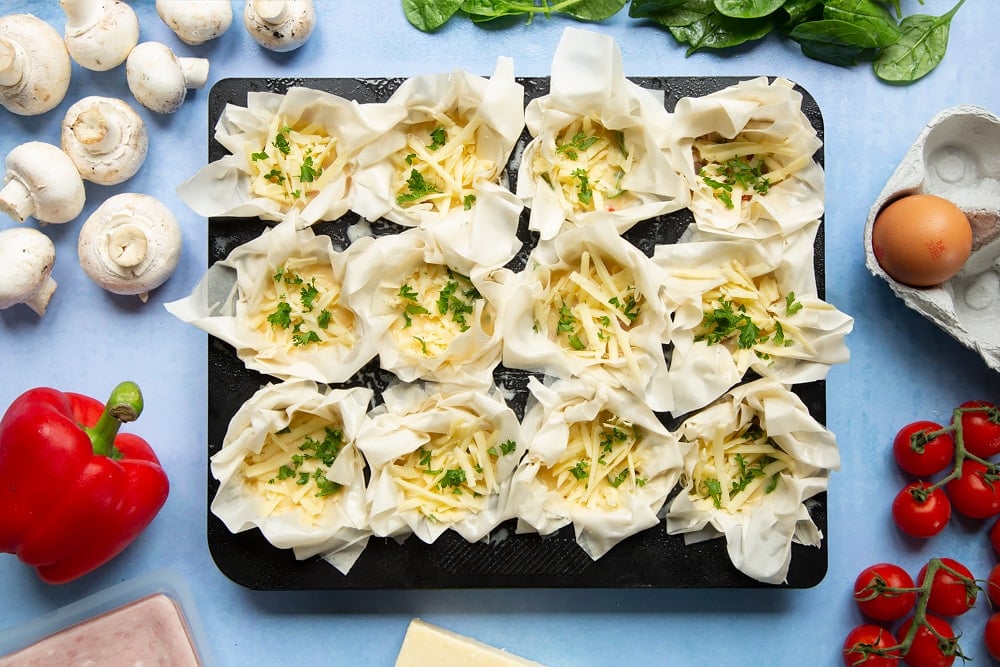 Filo pastry mini quiches - uncooked with cheese and parsley added to filo pastry cases.