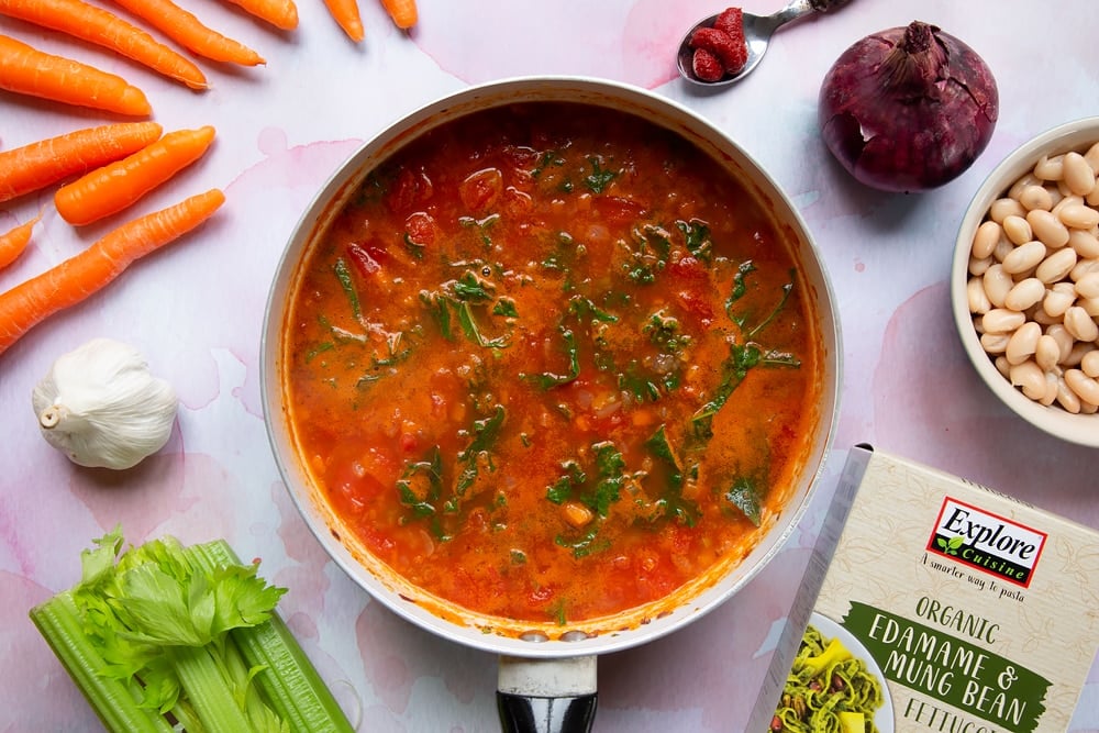 The ingredients have simmer for two minutes, the kale has wilted and the vegetable stock, tin of tomatoes, tomato puree, cooked carrots, celery, onion, garlic, oregano has combined in the frying pan.