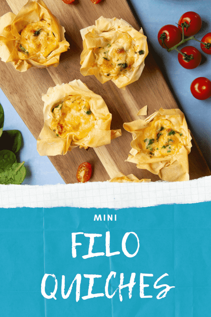 Overhead shot of the Filo Pastry Mini Quiches on a wooden board on a blue background. At the bottom of the image there's some text describing the image for Pinterest. 