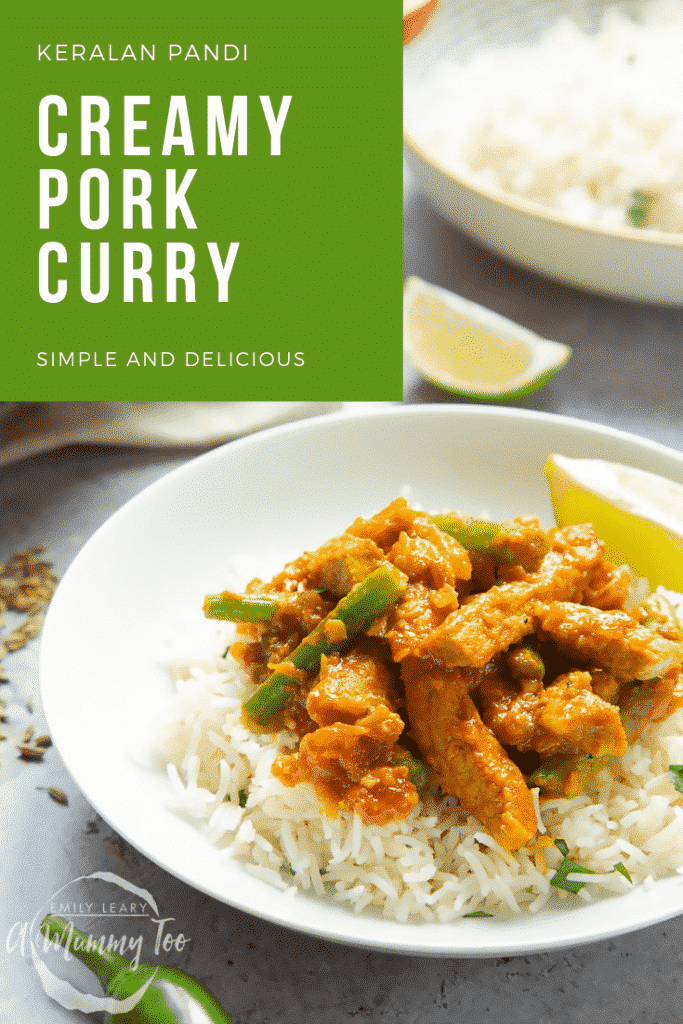 A shallow bowl of creamy pork curry rests on top of fluffy white rice, there is a slice of lime to accompany it. 