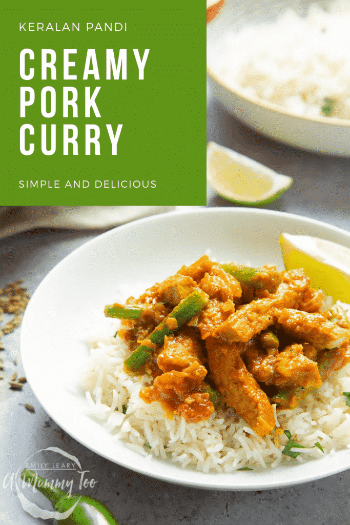 A shallow bowl of creamy pork curry rests on top of fluffy white rice, there is a slice of lime to accompany it.