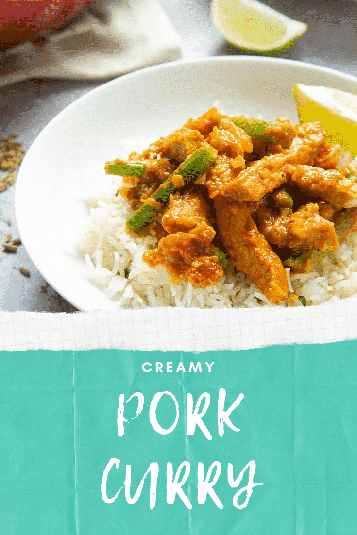 A bowl of creamy pork curry resting on top of fluffy rice in a bowl, accompanied by lime wedges.