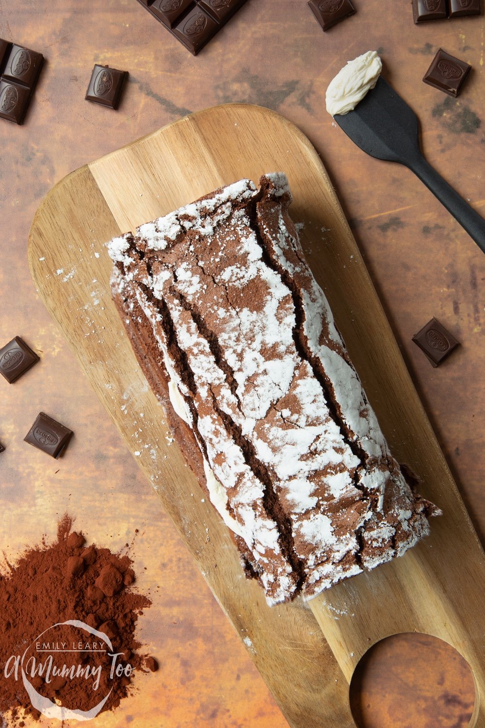 A fully rolled chocolate roulade arranged on a board.