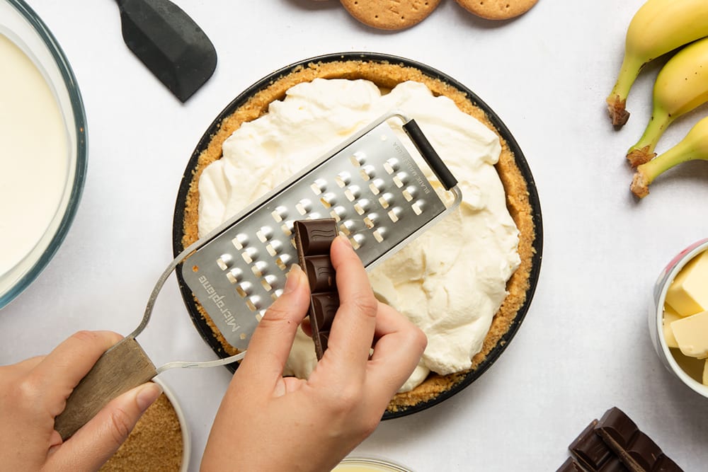 Grating dark chocolate on top of the whipped cream
