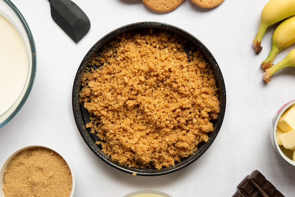 Crumbled biscuit in loose bottomed tin