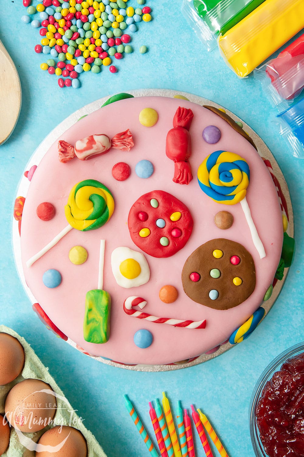 Sweet shop cake. Victoria sponge sandwich, covered with pink fondant and decorated with sugar paste candy sweets, cookies and treats. Surrounded by candy and sugarpaste