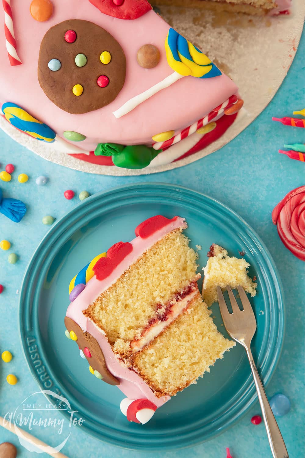 Sweet shop cake. A slice of Victoria sponge sandwich on a plate. The cake is covered with pink fondant and decorated with sugar paste candy sweets