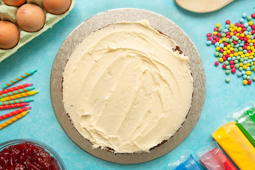 Victoria sponge on a cake board, spread with vanilla buttercream