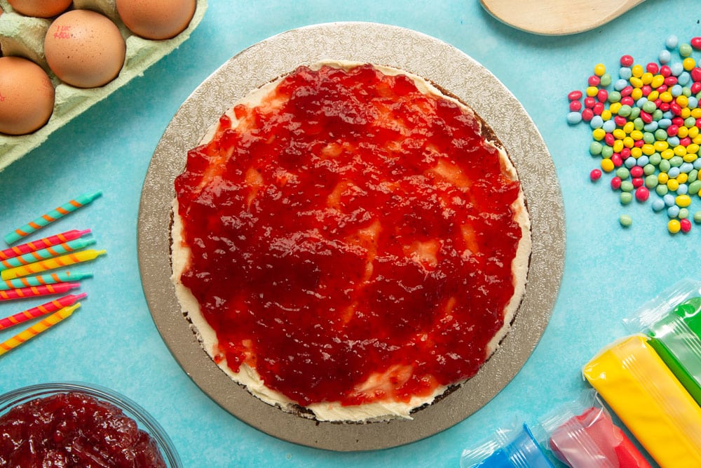 Victoria sponge on a cake board, spread with vanilla buttercream and strawberry jam