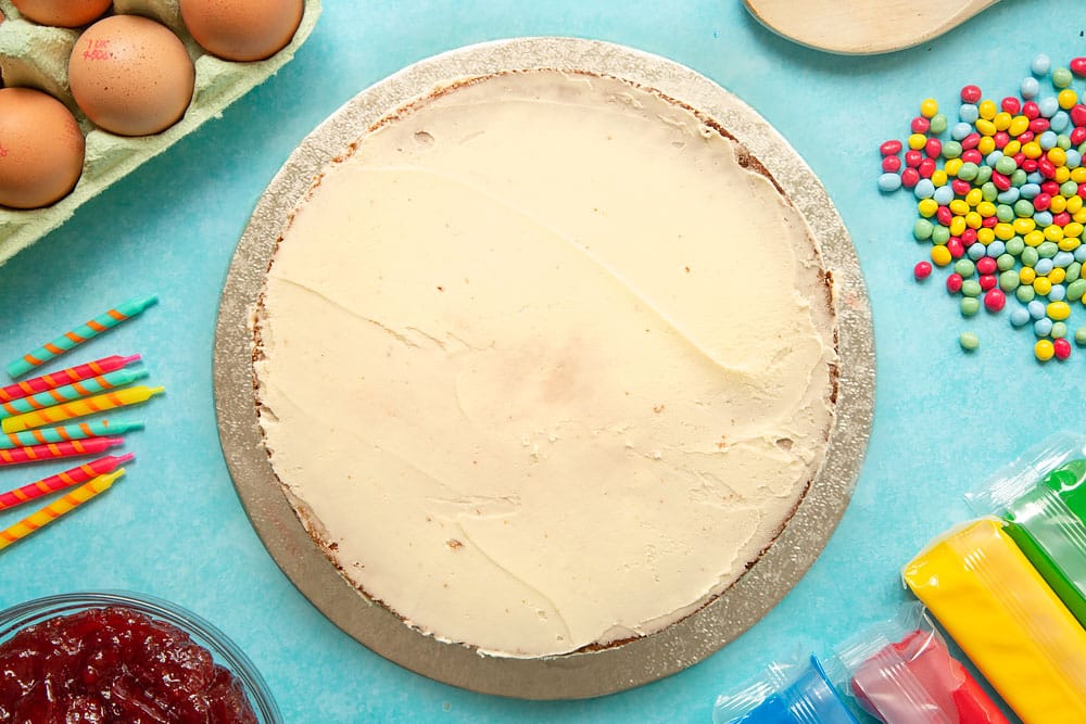 Victoria sponge sandwich on a cake board, covered all over with a thin layer of buttercream