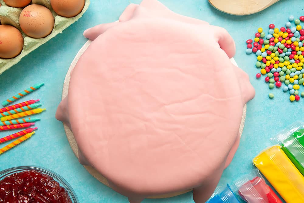 Victoria sponge sandwich on a cake board, covered all over with rolled out pink sugar paste