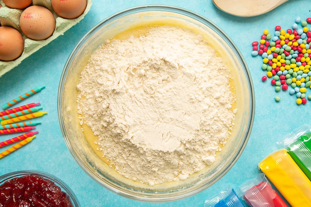 Eggs, vanilla, sugar and butter beaten together in a mixing bowl with self-raising flour on top