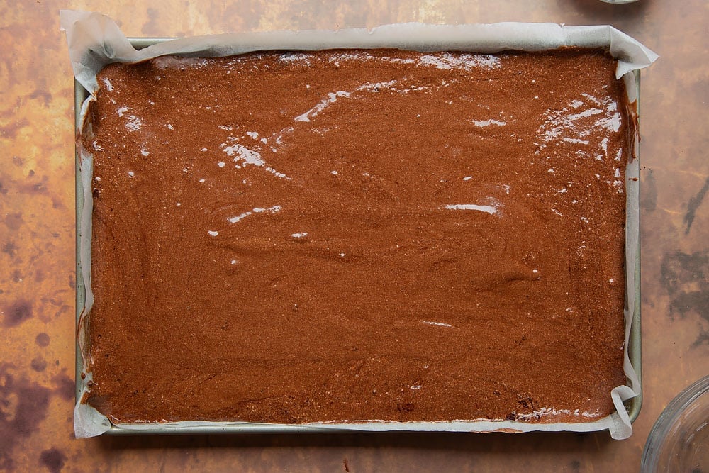 Chocolate roulade batter spread evenly in a lined swiss roll tin.