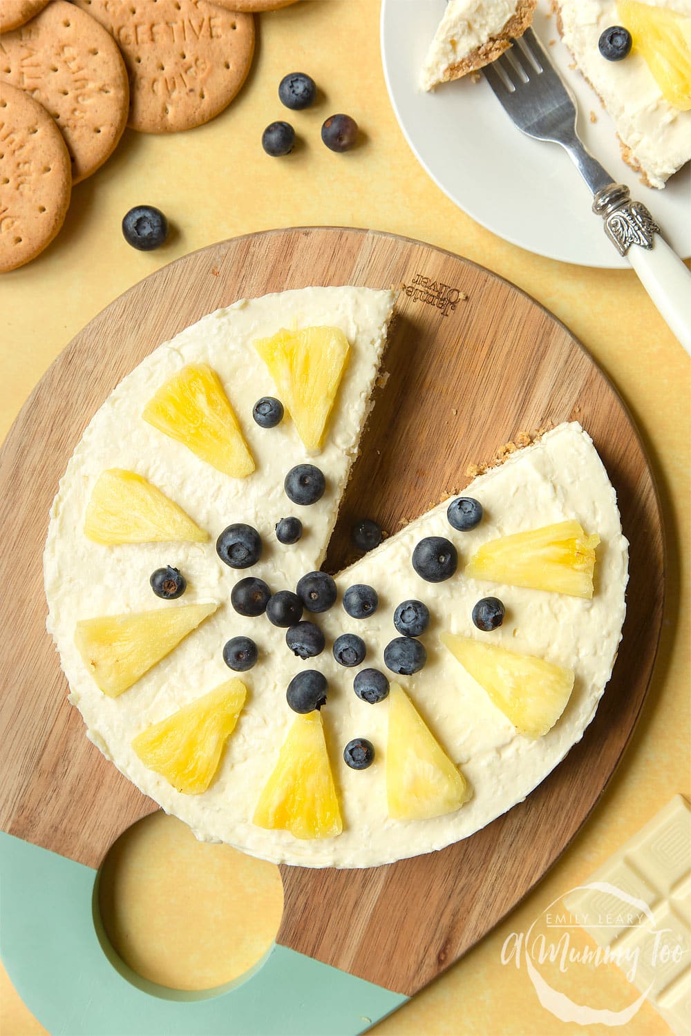 Extra special no-bake coconut cheesecake topped with pineapple pieces and blueberries. Once slice cut out.