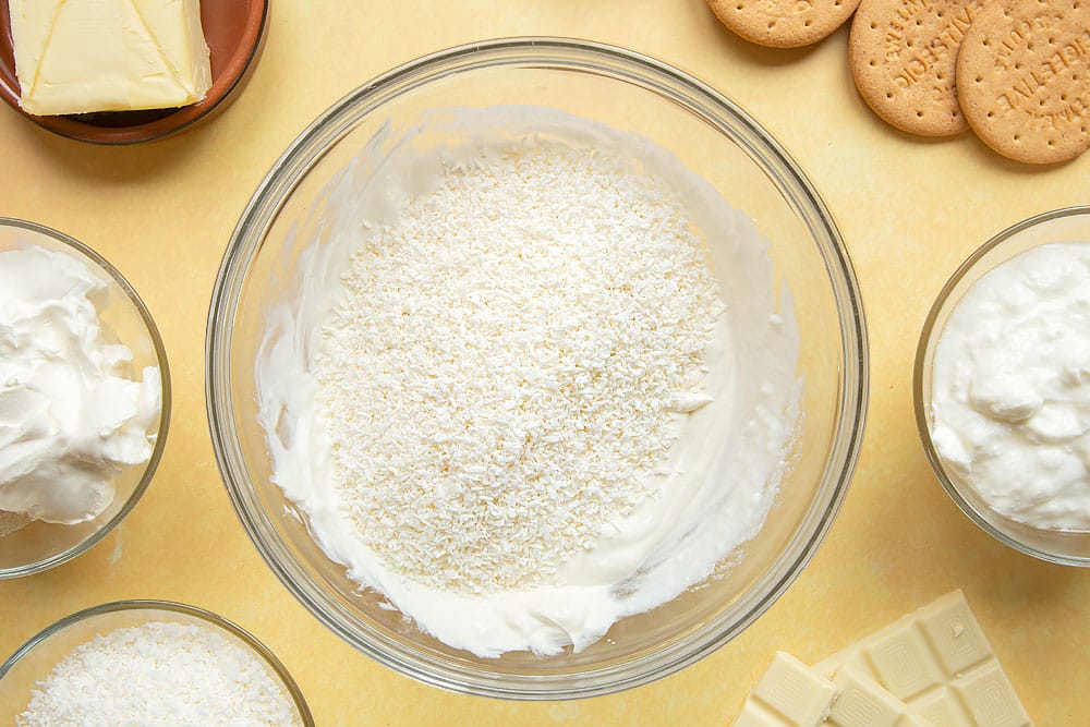 Cream cheese and yogurt whisked together in a large mixing bowl. Desiccated coconut added on top.
